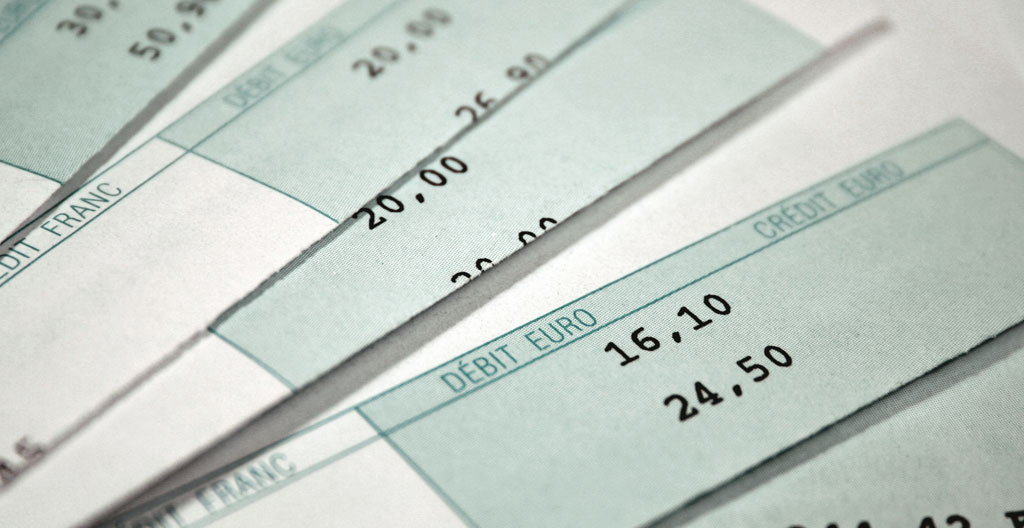 Gros plan sur des relevés bancaires professionnels annotés et une calculatrice posée sur un bureau